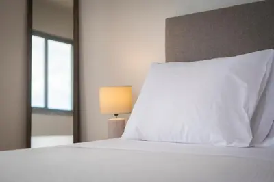 a white bed with a white pillow and a lamp at Casa da Baía Overlooking Funchal Bay in Funchal