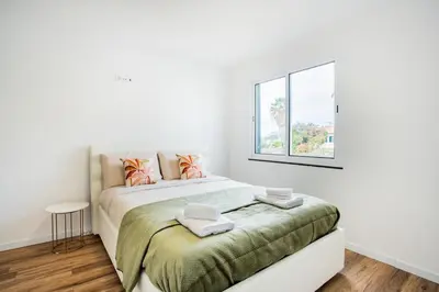 a white bedroom with a bed and a window at Madeira Melody in Funchal