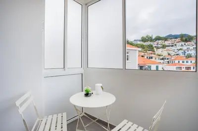 a white table and chairs in a white room with windows at Madeira Melody in Funchal