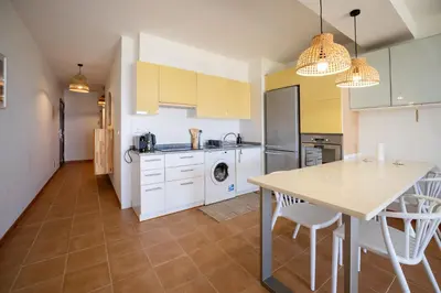 a kitchen with white cabinets and a table with chairs at Ohana - Casa de Praia by YOUR KEY in Porto Santo
