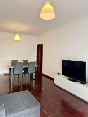 a living room with a television and a table with chairs at Ohana Funchal in Funchal