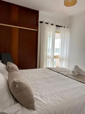 a bedroom with a large white bed with a window at Ohana Funchal in Funchal