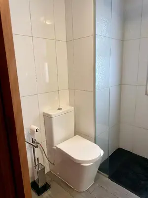 a bathroom with a toilet and a glass shower at Ohana Funchal in Funchal