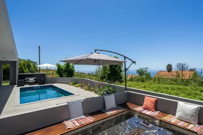 a backyard with a swimming pool and an umbrella at Vila da Ponta do Pargo by An Island Apart in Ponta do Pargo