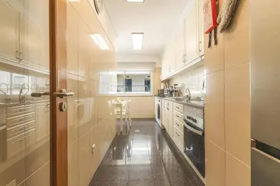 a large kitchen with white cabinets and a table at Senhora do Pilar by Atlantic Holiday in Santo António