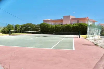 a tennis court with a net in front of a building at Apartamento Malino in Sagres