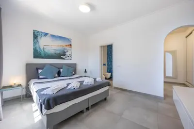 a bedroom with a large bed with blue pillows at Casa da Praça - Vila do Bispo, Algarve in Vila do Bispo