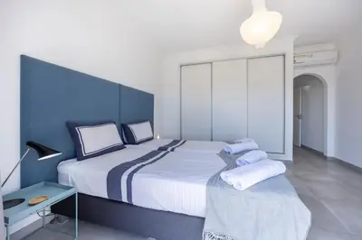 a bedroom with a large bed and a blue wall at Casa da Praça - Vila do Bispo, Algarve in Vila do Bispo