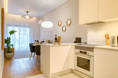 a kitchen with white cabinets and a living room at Funchal Acqua Blue 3O, a Home in Madeira in Funchal