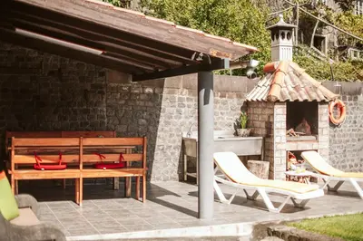 a patio with a table and chairs and a fireplace at Casa da Pedra by Amazing Madeira in Santana