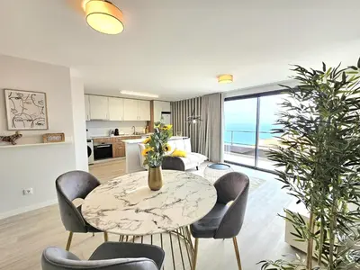 a living room with a table and chairs and a kitchen at Garajau Palace Sea View II by Rentallido in Caniço