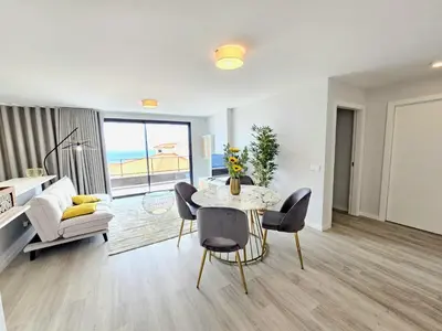 a living room with a table and chairs and a couch at Garajau Palace Sea View II by Rentallido in Caniço