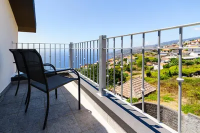 a chair on a balcony with a view of the ocean at Barreiro View in Ribeira Brava
