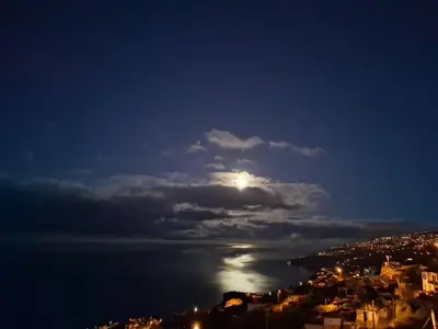 a moon in the sky over a city at night at Barreiro View in Ribeira Brava
