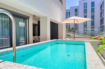 a swimming pool with an umbrella next to a building at Funchal Acqua Blue 3H, a Home in Madeira in Funchal