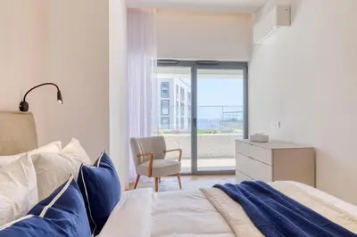 a bedroom with a bed and a chair and a window at Funchal Acqua Blue 3H, a Home in Madeira in Funchal