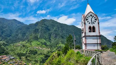 a clock tower on top of a hill with a mountain at Casa Teixeira by Holiday Rental Madeira in Senhora do Rosário