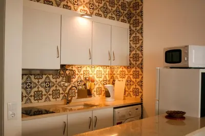 a kitchen with white cabinets and a white refrigerator at Apartamento Gois in Machico