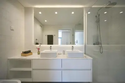 a white bathroom with two sinks and a shower at Madeira Acqua Suite in Funchal