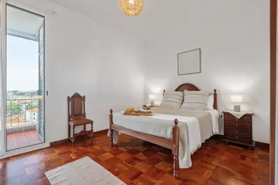 a white bedroom with a bed and a balcony at Casa Nóbrega, By OP in Funchal