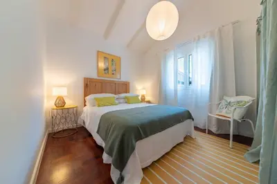 a bedroom with a bed and a chair in it at Casa Velha da Lagoa - Pássaro - by Mth in Ponta do Sol