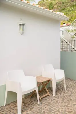 two white chairs and a wooden table on a patio at Casa Velha da Lagoa - Pássaro - by Mth in Ponta do Sol