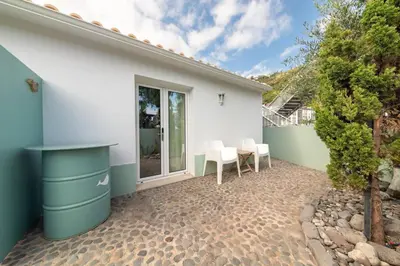 a patio with a table and chairs next to a house at Casa Velha da Lagoa - Pássaro - by Mth in Ponta do Sol