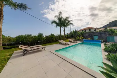 a swimming pool with two chairs and a pool at Casa Velha da Lagoa - Pássaro - by Mth in Ponta do Sol