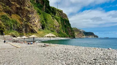 a group of people sitting on a beach with umbrellas at Casa Velha da Lagoa - Pássaro - by Mth in Ponta do Sol