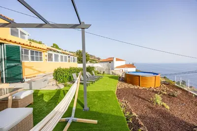 a hammock on a lawn in front of a house at Hibiscus House by YOUR KEY in Calheta
