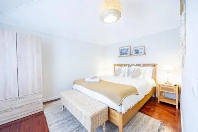a white bedroom with a bed and a table at Hibiscus House by YOUR KEY in Calheta