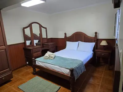 a bedroom with a bed and two night stands and a chair at Villa Pedro, Big House in Calheta