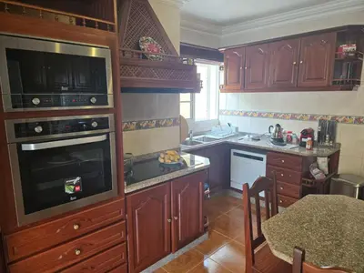 a kitchen with wooden cabinets and a table in it at Villa Pedro, Big House in Calheta