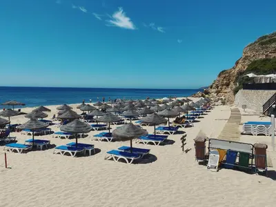 a bunch of chairs and umbrellas on a beach at VilaMar in Salema