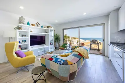 a living room with a couch and a kitchen with a view at Burgau Beach Apartment in Burgau