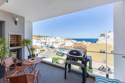 a grill on a balcony with a view of a city at Burgau Beach Apartment in Burgau