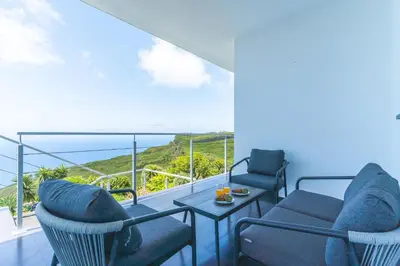 a balcony with chairs and a table and a view of the ocean at Cape View Villa by Atlantic Holiday in Ponta do Pargo