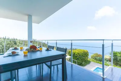 a dining table with a view of the ocean from a house at Cape View Villa by Atlantic Holiday in Ponta do Pargo