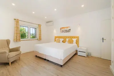 a white bedroom with a bed and a chair at Casa Tambeim in Montinhos da Luz