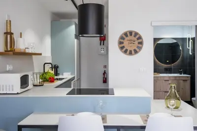 a kitchen with white counters and a table with chairs at Casa das Rosas - By Wehost in Santa Cruz