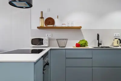 a white kitchen with blue cabinets and a microwave at Casa das Rosas - By Wehost in Santa Cruz