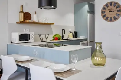a kitchen with a table with white chairs and a clock at Casa das Rosas - By Wehost in Santa Cruz