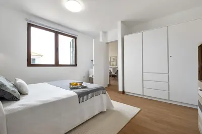 a white bedroom with a large bed and a window at Casa das Rosas - By Wehost in Santa Cruz