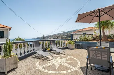 a patio with chairs and an umbrella on a balcony at Casa das Rosas - By Wehost in Santa Cruz