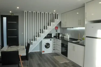 a kitchen with a washer and dryer under the stairs at Nature Apartment 2 with Pool in Arco da Calheta