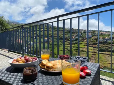 a table with a plate of food and orange juice at Rocha House in Calheta