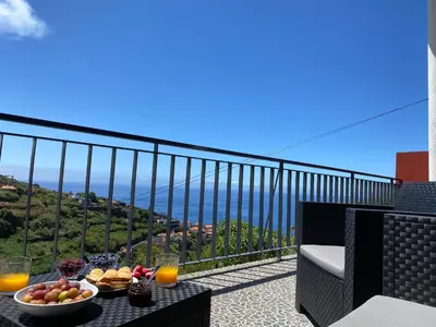 a table with a bowl of fruit on a balcony at Rocha House in Calheta