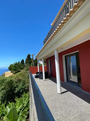 a house with a balcony with the ocean in the background at Rocha House in Calheta