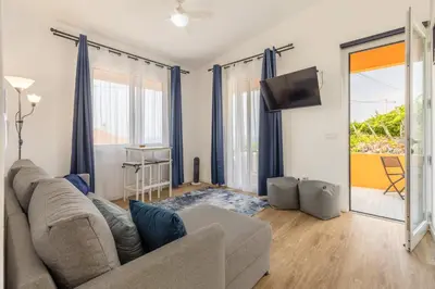a living room with a couch and a tv at Coastal São Vicente Mountain & Sea View Hideaway with Free Parking in São Vicente