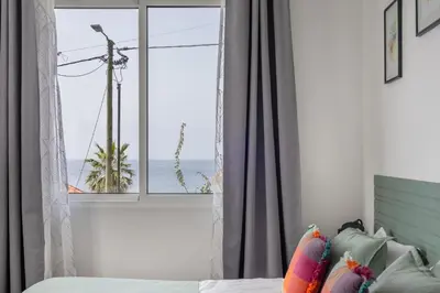 a bedroom with a window with a view of the ocean at Coastal São Vicente Mountain & Sea View Hideaway with Free Parking in São Vicente